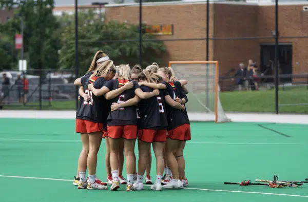 Picture of lacrosse players showing teamwork in a huddle.